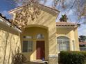 Close-up of a single-story home with a classic red front door and manicured bushes at 7456 Oatman Ln, Las Vegas, NV 89120