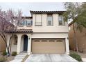 Charming two-story home with a tan stucco exterior, a two-car garage, and blossoming trees at 7735 Pista Way, Las Vegas, NV 89179