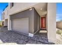 Close-up view of a modern home's gray garage door and red front door, accented by textured brickwork at 8629 Ensworth St # 111, Las Vegas, NV 89123