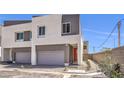 Contemporary two-story home with a gray garage door and red front door, landscaped with desert plants at 8629 Ensworth St # 111, Las Vegas, NV 89123