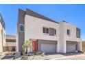 Newly built home with modern architecture, gray garage doors, and a vibrant red front door at 8629 Ensworth St # 112, Las Vegas, NV 89123