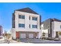 Contemporary home with a gray and white facade, a two-car garage and a neatly paved driveway at 8629 Ensworth St # 113, Las Vegas, NV 89123
