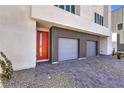 Paver driveway leading to a two-car garage and a red-framed glass door with modern landscaping at 8629 Ensworth St # 114, Las Vegas, NV 89123