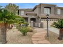 Inviting home exterior with desert landscaping, a stone walkway, and an elegant gated entrance with mature palm trees at 9108 Ghost Mountain Ave, Las Vegas, NV 89129