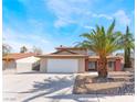Two-story home with a two-car garage and a large palm tree in the front yard under a partly cloudy sky at 1009 N Tenaya Way, Las Vegas, NV 89128