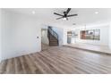 Spacious living room with wood-look flooring, a staircase, a window, and an open view to the kitchen at 1009 N Tenaya Way, Las Vegas, NV 89128