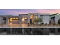 Striking modern home featuring an attached garage, manicured landscaping, and a welcoming entryway at dusk at 10794 White Clay Dr, Las Vegas, NV 89135