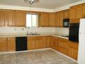 Functional kitchen with oak cabinets, tile floors, black appliances, and a window above the sink at 313 View Dr, Las Vegas, NV 89107