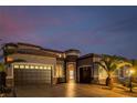 Warm home exterior with a two-car garage, desert landscaping, and entry tower at 7682 Rafter Ct, Las Vegas, NV 89139