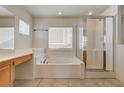 Bright bathroom featuring a separate glass shower, soaking tub, and tiled floors at 9013 Semillon St, Las Vegas, NV 89148