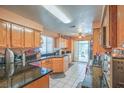 Well-lit kitchen with granite countertops, oak cabinets, a gas stove, and white tiled floors at 2700 Brienza Way, Las Vegas, NV 89117