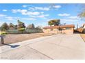 Inviting single-story home with a lengthy driveway and a secure chain-link fence, complemented by desert landscaping at 4970 E Van Buren Ave, Las Vegas, NV 89110