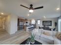 Open-concept living area featuring a kitchen with island, dining space, and comfortable seating around a ceiling fan at 5766 Remy Rain St, Las Vegas, NV 89148