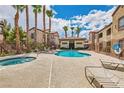 Community pool and spa area with lounge chairs and lush landscaping under sunny skies at 9580 W Reno Ave # 211, Las Vegas, NV 89148