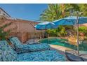 Private backyard with lounge chairs, beautiful pool, and shade umbrellas, perfect for relaxation at 1516 Barrington Oaks St, North Las Vegas, NV 89084