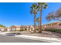 Single-story home with desert landscaping, palm trees and two car garage on a sunny day at 1821 Eagle Mesa Ave, Henderson, NV 89012