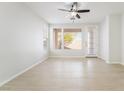 Bright living room featuring a ceiling fan, backyard access, and light-colored tile floors at 4546 Regalo Bello St, Las Vegas, NV 89135