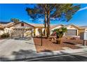 Charming home exterior with a well-maintained yard, mature trees, and two-car garage at 5448 Cove Point Dr, Las Vegas, NV 89130