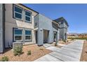 Exterior angle of townhome featuring desert landscaping and a sidewalk leading to the front door at 6172 Aster Garden St # 139, North Las Vegas, NV 89081