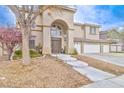 Two-story home featuring desert landscaping, an arched entryway, and an attached three-car garage at 694 Tomscott Ave, Henderson, NV 89052