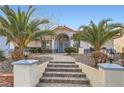 Inviting entryway with tiled steps, mature landscaping, and an arched entrance highlighting this lovely home at 905 White Thunder St, Henderson, NV 89002