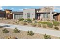 A modern home is showcased, featuring a landscaped front yard, a two-car garage with translucent glass, and a contemporary facade at 9938 Regency Canyon Way, Las Vegas, NV 89148