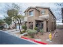 Two-story tan home with landscaped front yard and covered porch offers excellent curb appeal at 10323 Hardy Falls St, Las Vegas, NV 89141