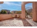 Inviting outdoor patio with brick flooring, seating, and an arched entrance at 10478 Beallsville St, Las Vegas, NV 89141