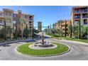 Beautifully landscaped community entrance with circular water feature and elegant residential buildings at 15 Via Mantova # 308, Henderson, NV 89011