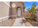 Arched entryway with a white front door, desert plants, and a decorative fence for a charming welcome at 1892 Falcon Ridge St, Las Vegas, NV 89142
