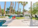 Backyard showcasing a serene seating area with a swing near the pool, accented by colorful chairs and mature palm trees at 2339 Prometheus Ct, Henderson, NV 89074
