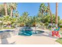 Gorgeous pool with a unique stone-clad jacuzzi, complemented by lush landscaping and sunny seating at 2339 Prometheus Ct, Henderson, NV 89074