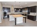Gourmet kitchen features dark cabinetry, granite countertops, stainless steel appliances, and island with seating at 2822 Poseidon Shore Ave, Henderson, NV 89052