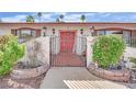 A front entrance featuring a secure gate, charming red door, and decorative planters at 3681 S Rosecrest Cir, Las Vegas, NV 89121