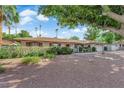 A charming single-story home with desert landscaping, mature trees, and a red front door at 3681 S Rosecrest Cir, Las Vegas, NV 89121