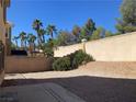 Desert backyard with a privacy wall, mature palm trees, and low-maintenance landscaping at 405 Center Green Dr, Las Vegas, NV 89148