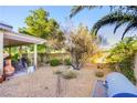 Backyard featuring gravel landscaping, mature trees, a built in hot tub, and a covered patio at 7172 Painted Paradise St, Las Vegas, NV 89131