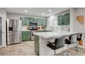 Modern kitchen features sage green cabinets, stainless steel appliances, quartz countertops, and stylish bar seating at 11157 Mezzana St, Las Vegas, NV 89141
