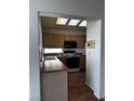 Functional kitchen with wood cabinetry, and black appliances, illuminated by a skylight at 2118 Chapman Ranch Dr, Henderson, NV 89012