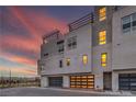 Modern townhome exterior with a rooftop patio, garage, and clean architectural lines at sunset at 3346 Esker Ridge Ave, Henderson, NV 89044