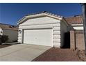 View of the garage of the home with a white garage door, brown rock landscaping, and a concrete driveway at 3761 Tohono Canyon St, Las Vegas, NV 89147