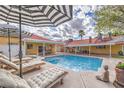 Stunning backyard oasis with a pool, lounge chairs, umbrellas, lush landscaping, and comfortable seating, perfect for relaxation and entertaining at 4170 Ridgecrest Dr, Las Vegas, NV 89121