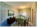 Staged dining room with green chairs, a modern table and decorative wallpaper at 648 Utah St, Boulder City, NV 89005