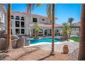 Beautiful backyard oasis with a sparkling pool, mature palm trees, and a covered patio area at 3465 Pama Ln, Las Vegas, NV 89120