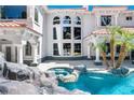 Resort-style pool area with a spa, waterfall feature, and lush landscaping creating a private oasis at 3465 Pama Ln, Las Vegas, NV 89120