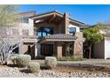 Gorgeous home with a stone facade, manicured landscaping and covered entryway at 64 Promontory Ridge Dr, Las Vegas, NV 89135