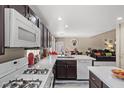 Well-lit kitchen featuring dark wood cabinetry, white appliances, and ample countertop space, seamlessly flowing into the living area at 8100 Artistic Heights Ct, Las Vegas, NV 89143
