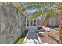 Close-up shot of the front door and entryway with stone decor, desert landscaping, and palm trees at 897 Cavaison Ave, Las Vegas, NV 89123