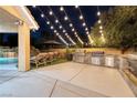 Outdoor kitchen and seating with string lights, ideal for backyard entertaining at 5870 N Durango Dr, Las Vegas, NV 89149