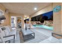 Covered patio with comfortable seating overlooking a backyard pool with waterfalls at 5870 N Durango Dr, Las Vegas, NV 89149